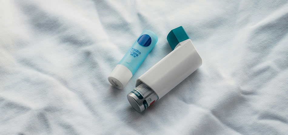 close up of inhaler and chapstick on white bedspread, auer perspectives